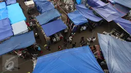 Pengunjung melewati pedagang korban kebakaran yang berjualan di area parkir Pasar Senen, Jakarta, Rabu (8/2). Belum tersedianya tempat penampungan sementara membuat para pedagang terpaksa mendirikan tenda lapak. (Liputan6.com/Immanuel Antonius)
