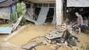 Seorang pria membersihkan toko mereka yang furniturnya rusak akibat terendam banjir di luar toko mereka di Hulu Langat, di luar Kuala Lumpur, Malaysia, Minggu (19/12/2021). Kuala Lumpur dan perkampungan sekitarnya dilanda banjir akibat hujan deras selama dua hari. (AP Photo/Vincent Thian)