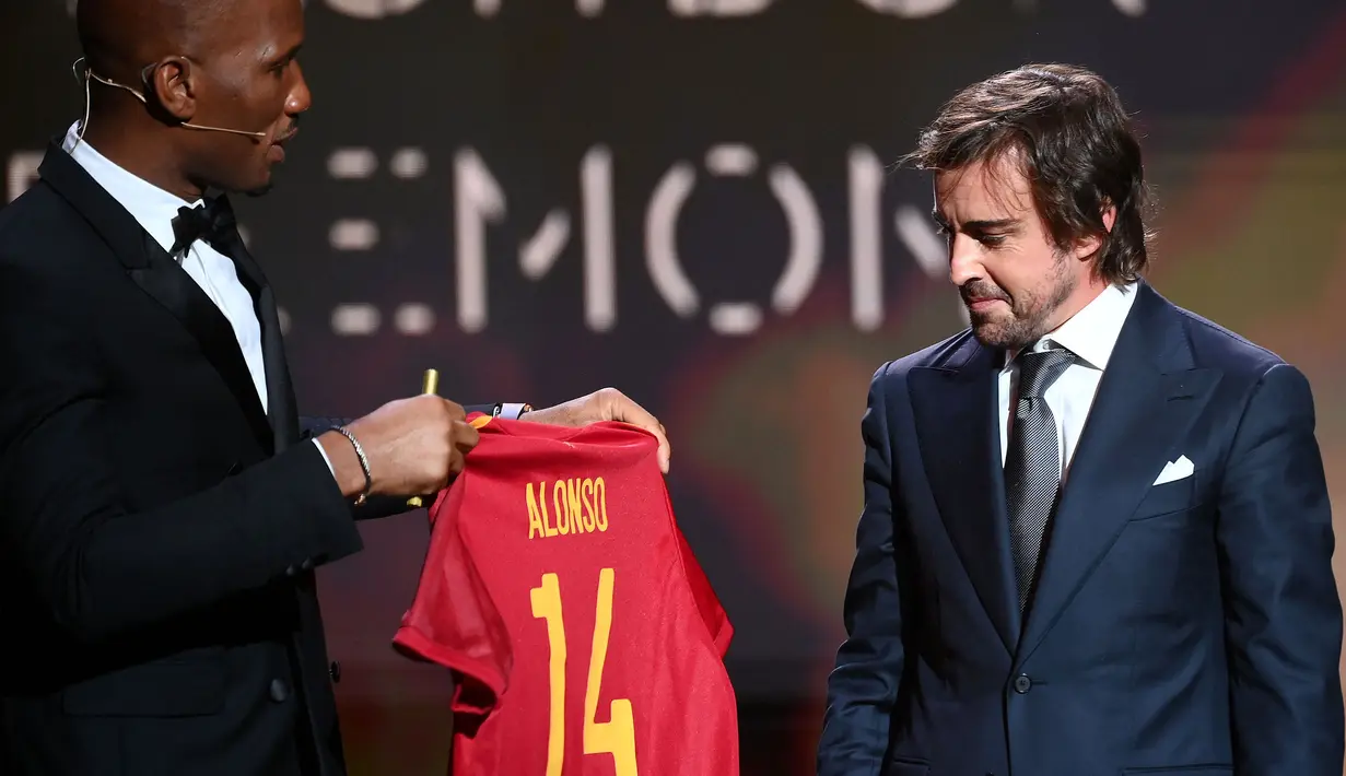 Pada acara tersebut, Didier Drogba juga terlihat menyerahkan kenang-kenangan berupa jersey Timnas Spanyol kepada juara dunia F1 dua kali, Fernando Alonso. Alonso dan Ocon diketahui akan melakoni balapan di GP Arab Saudi 2021 pada akhir pekan ini. (AFP/Franck Fife)