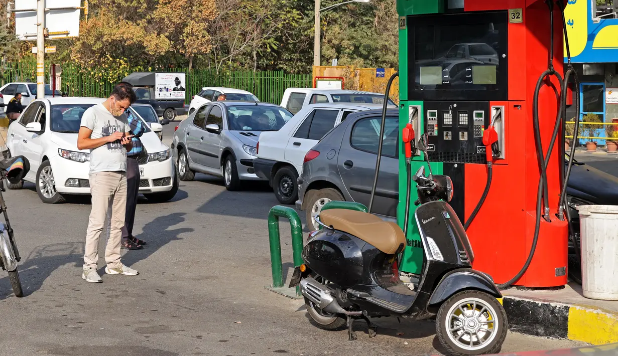 Mobil dan sepeda motor mengantre untuk mengisi bahan bakar di sebuah SPBU di tengah gangguan sistem distribusi bensin secara nasional di Teheran, Iran, Selasa (26/10/2021). Sebuah serangan siber mengganggu distribusi bensin di SPBU seluruh Iran yang menyebabkan penghentian layanan. (Atta KENARE/AFP)