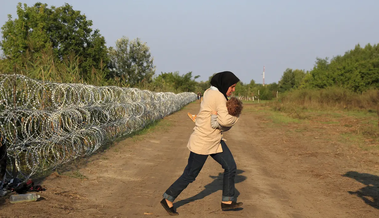 Imigran Suriah berlari usai berhasil melewati pagar berduri di wilayah Hungaria dekat perbatasan Serbia, wilayah Roszke, Kamis (27/8/2015). Hungaria berencana untuk memperketat perbatasan bagian selatannya dari para pengungsi. (REUTERS/Bernadett Szabo)