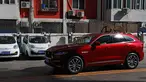 Sebuah mobil SUV warna merah melintas di depan mobil listrik model lama yang diparkir di stasiun pengisian listrik di rumah hunian Beijing (14/04/2017). Penjualan mobil kesulitan karena minimnya stasiun pengisian listrik. (AP Photo / Andy Wong)