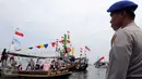 Seorang petugas mengamati saat para nelayan bersama keluarganya mengikuti sedekah bumi Nadran di Muara Angke, Jakarta, Minggu (13/12). Tradisi ini sebagai ungkapan rasa syukur kepada Tuhan YME atas hasil laut yang diperoleh. (Liputan6.com/Helmi Afandi)