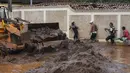Orang-orang berjalan di jalan yang banjir di Raposos, negara bagian Minas Gerais, Brasil, Selasa (11/1/2022). Tanah longsor akibat hujan deras telah menewaskan sedikitnya 12 orang dan pihak berwenang sedang memantau bendungan yang bisa jebol. (AP Photo/Eugenio Savio)