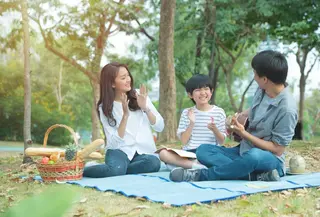Sebuah keluarga kecil yang terdiri dari ayah, ibu, dan seorang anak laki-laki sedang mengadakan piknik di taman (Foto Dok: Freepik/mkitina4).