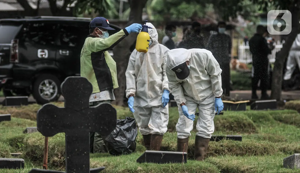 Petugas menyemprotkan disinfektan di area makam pasien Covid-19 di TPU Pondok Kelapa, Jakarta, Selasa (13/7/2021). Tim Koalisi Warga LaporCovid-19 mencatat sebanyak 451 pasien Covid-19 meninggal saat menjalani isolasi mandiri. (merdeka.com/Iqbal S Nugroho)