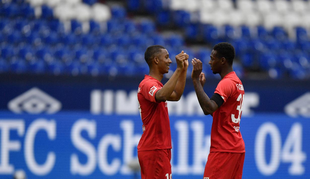 Pemain Augsburg, Felix Uduokha dan Reece Oxford merayakan kemenangan atas Schalke 04 pada laga Bundesliga di Veltins-Arena, Minggu (24/5/2020). Augsburg menang dengan skor 3-0 atas Schalke 04. (AP/Martin Meissner)