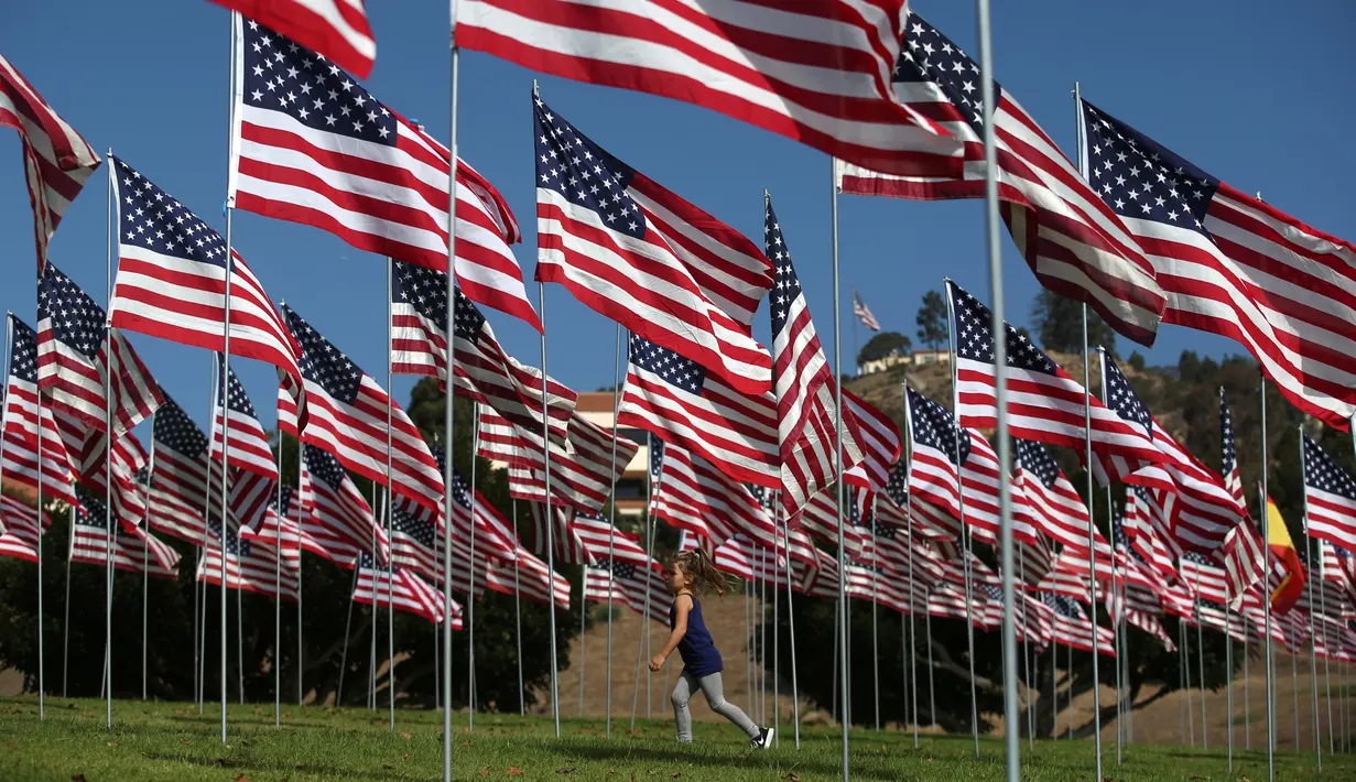Seorang anak perempuan berjalan diantara 3.000 bendera AS pada peringatan 15 tahun bagi para korban 11 September 2001 di Malibu, California, (11/09). Ribuan bendera AS juga terbang tinggi di New York.  (REUTERS/Lucy Nicholson)