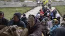 Orang-orang menerima makanan dari sebuah gereja di kota Borodyanka, sekitar 40 mil barat laut Kiev, Ukraina, pada hari Minggu, 10 April 2022. Invasi Rusia ke Ukraina hingga saat ini telah berlangsung selama 46 hari. (AP Photo/Petros Giannacouris)