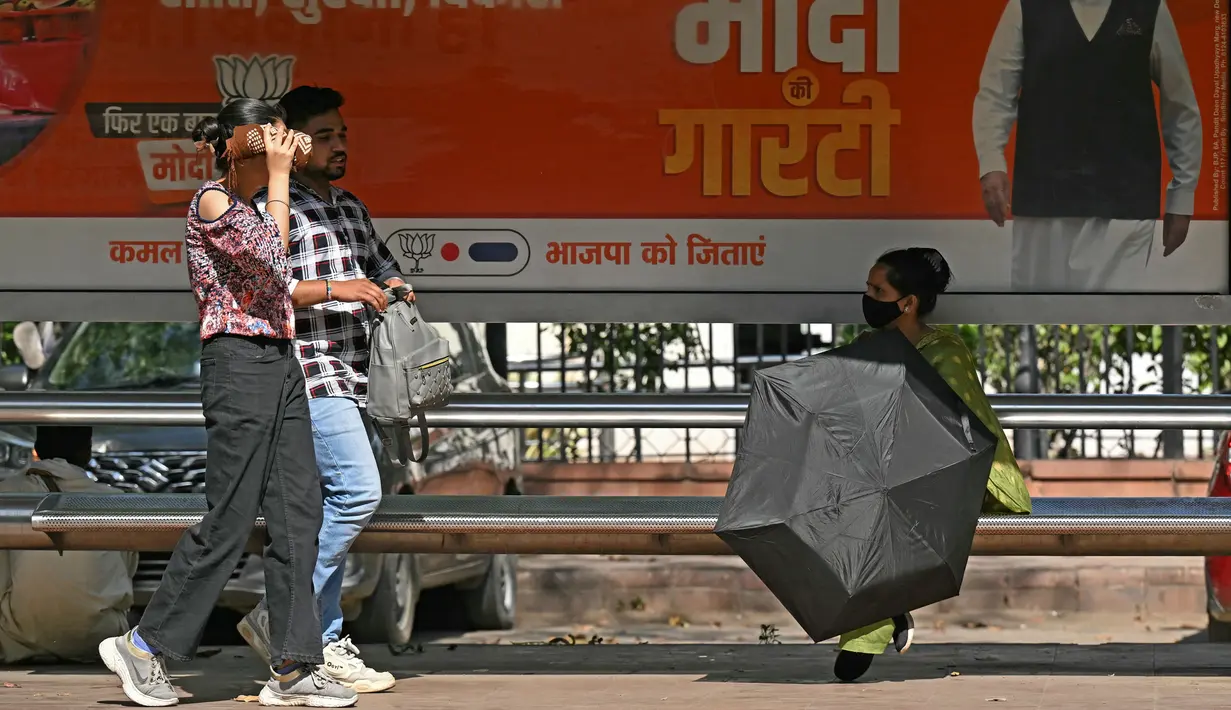 Seorang wanita memegang payung sambil menunggu bus di sebuah halte bus pada hari musim panas di New Delhi pada tanggal 25 April 2024. (Money SHARMA/AFP)