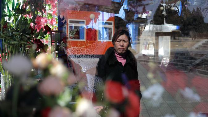 Seorang wanita terlihat di kaca jendela sebuah kios yang menjual bunga dalam perayaan Hari Perempuan Internasional di Pyongyang, Korea Utara, Jumat (8/3). (AP Photo/Dita Alangkara)