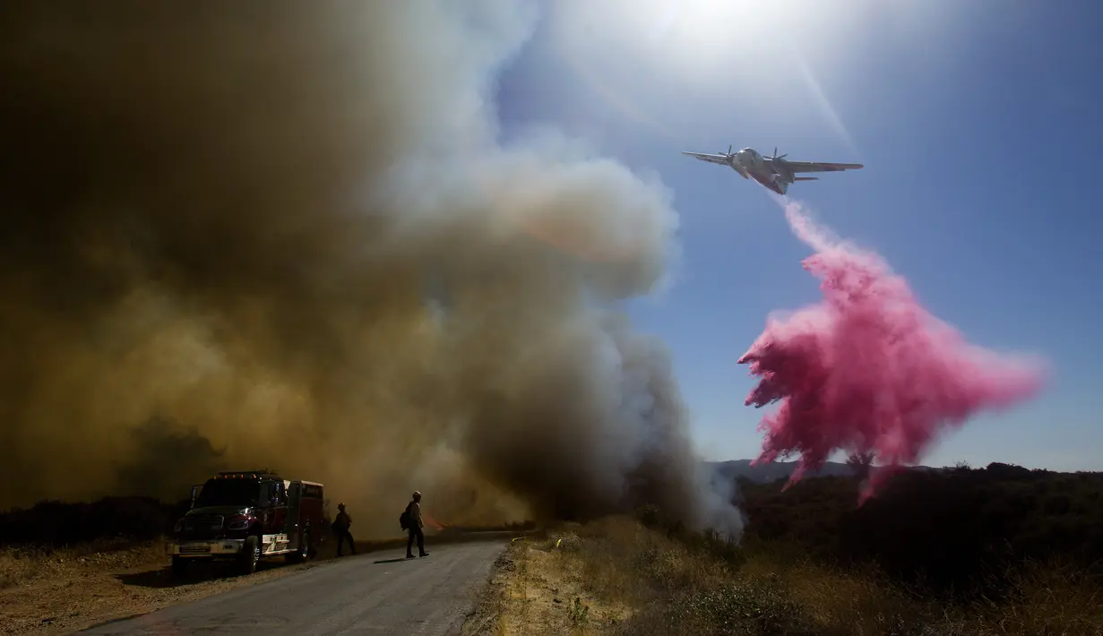 Sebuah kapal tanker menjatuhkan air saat memadamkan api di Cherry Valley, California (1/8/2020). Sebanyak 7.800 warga dievakuasi  akibat kebakaran hutan yang menghanguskan sekitar 4.000 hektar lahan pada akhir pekan kemarin. (AP Photo/Ringo H.W. Chiu)