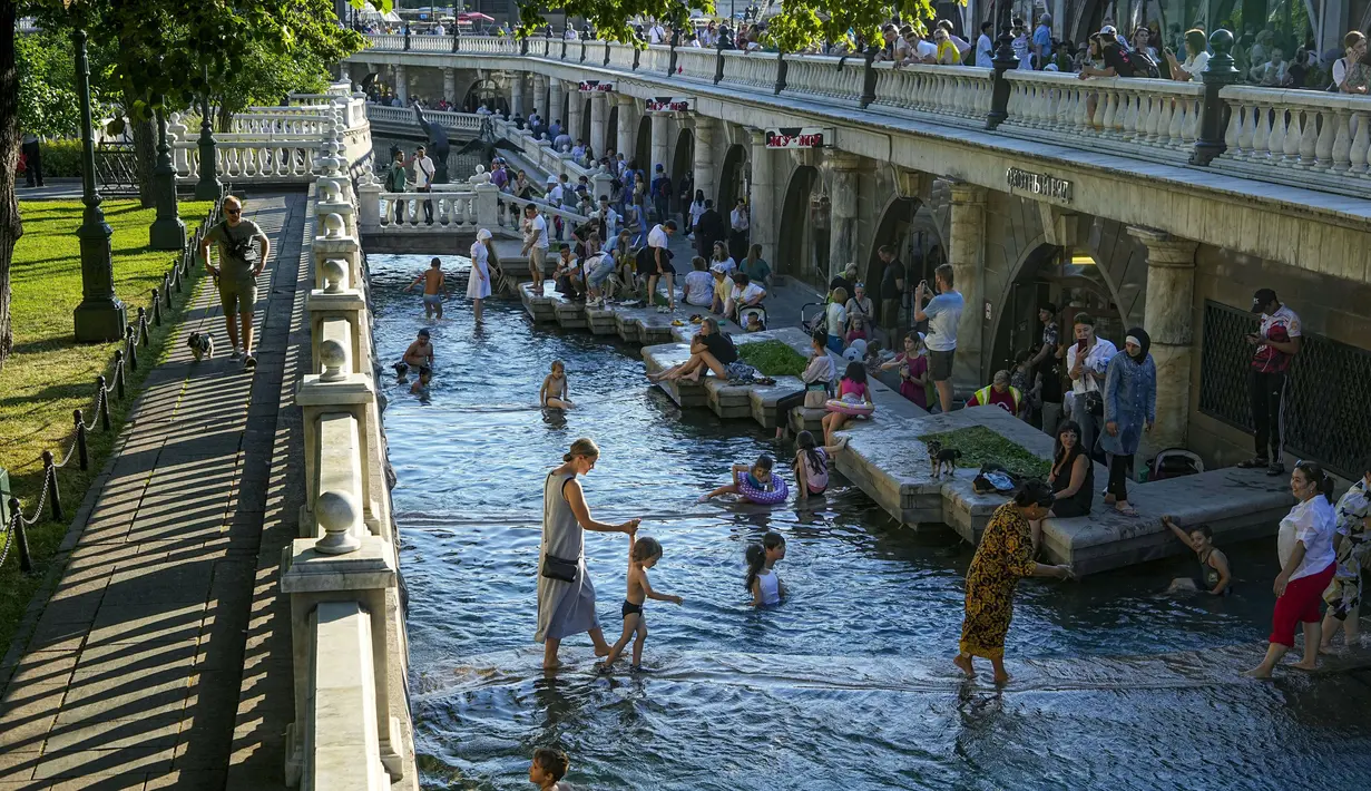 Suasana saat anak-anak menyejukkan diri di air Sungai Neglinnaya untuk menikmati penghujung hari yang panas di dekat Tembok Kremlin, Moskow, Rusia, 3 Juli 2022. Cuaca panas di Moskow datang dengan perkiraan suhu mencapai 30 derajat Celcius (86 Fahrenheit). (AP Photo/Alexander Zemlianichenko)