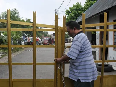 Seorang warga perumahan Eks Yon Angkub, Cililitan Besar, Jakarta, menggembok gerbang perumahan sebagai bentuk penolakan eksekusi rumah, Rabu (14/9).  Eksekusi rumah di kawasan itu mendapat penolakan warga. (Liputan6.com/Yoppy Renato)