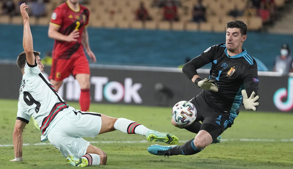 Penyerang timnas Portugal, Andre Silva dan kiper Belgia, Thibaut Courtois berebut bola babak 16 besar Euro 2020 di Estadio La Cartuja, Sevilla, Spanyol, Senin (28/6/2021) dini hari WIB. Belgia mendepak juara bertahan Portugal berkat kemenangan 1-0. (AP Photo/Thanassis Stavrakis, Pool)