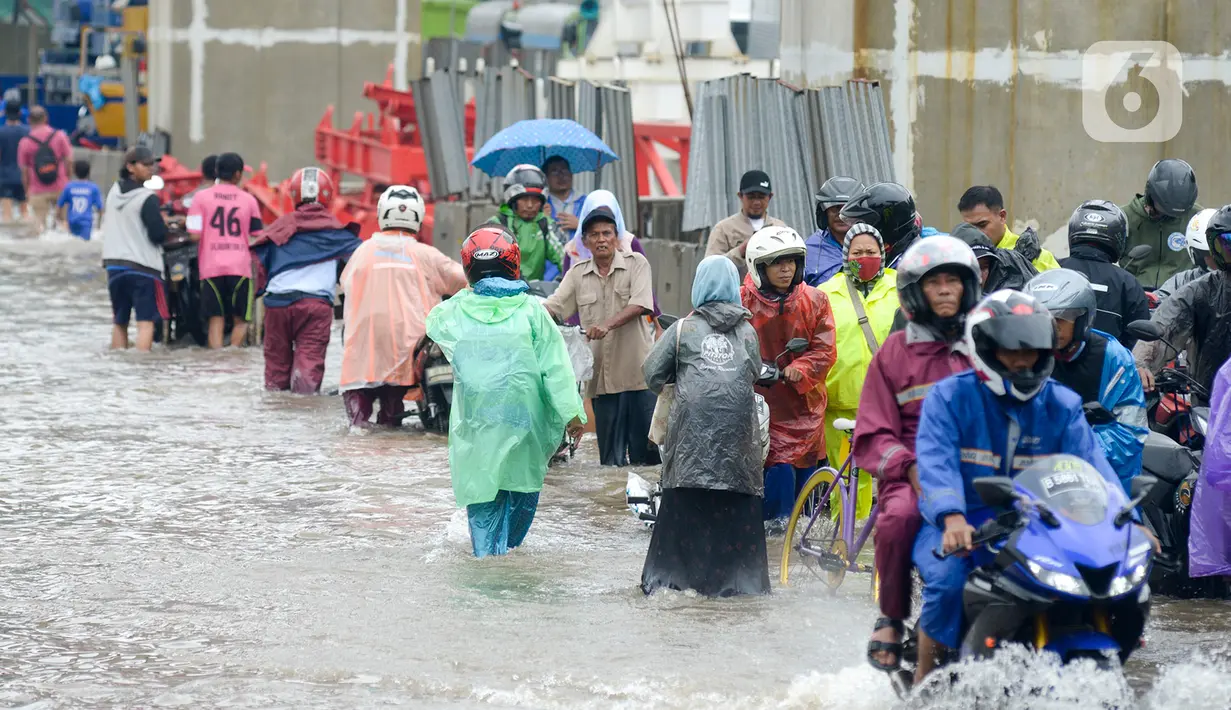 Sejumlah pengendara dan warga melintasi banjir di Jalan Raya Bekasi, Jakarta Timur, Selasa (25/2/2020). Banjir akibat hujan yang melanda Bekasi sejak Selasa (25/2) dini hari memutus beberapa titik jalan raya di wilayah setempat. (merdeka.com/Imam Buhori)