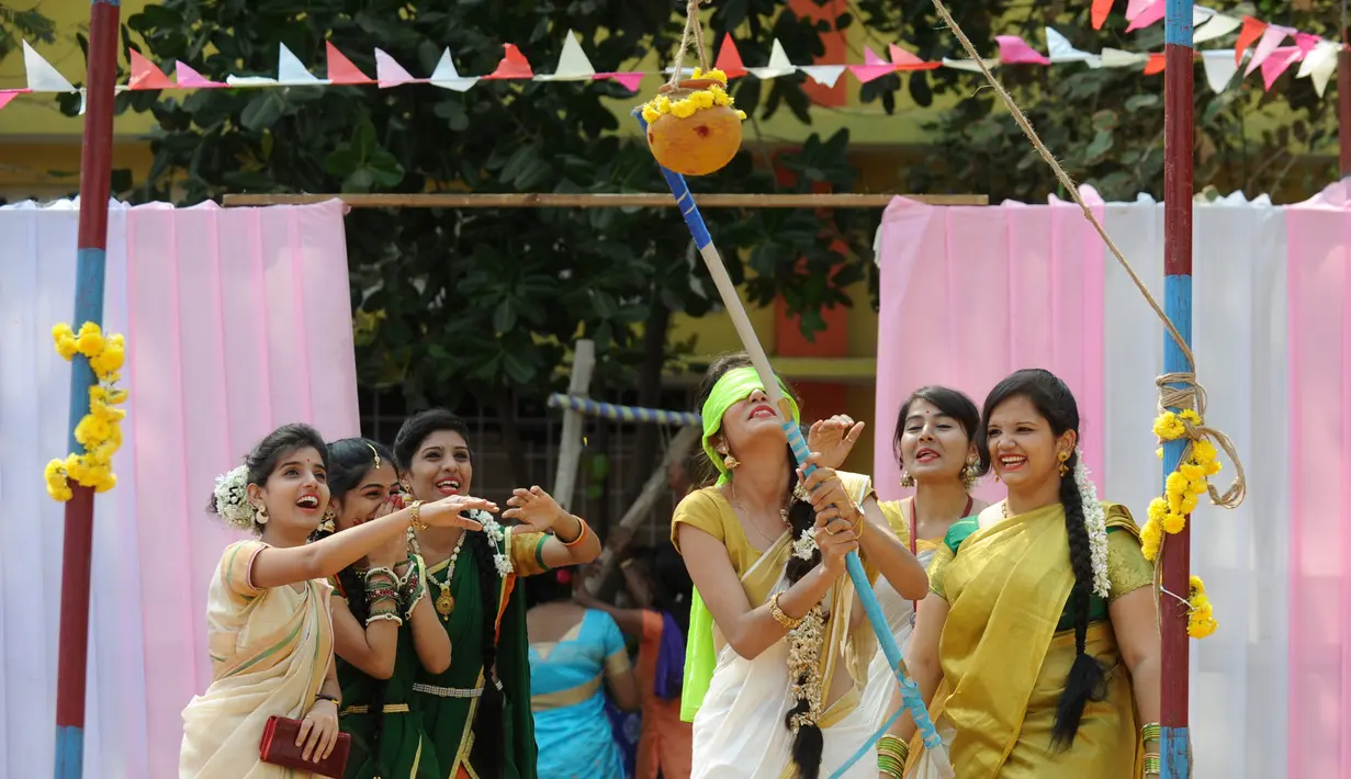 Seorang Wanita India berusaha memecahkan pot dengan mata tertutup pada perayaan Pongal di perguruan tinggi di Chennai, India (11/1). Perayaan Pongal merupakan bagian dari  festival panen Tamil yang diadakan selama empat hari. (AFP Photo/Arun Sankar)