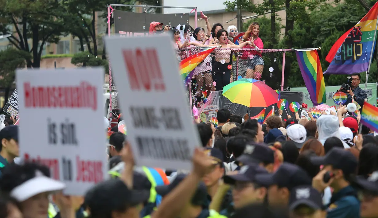 Seorang warga membentangkan poster anti-gay ditengah kerumunan peserta parade 'Gay Pride' di Seoul, Korea Selatan (15/7). Kelompok anti-gay ini mendesak kaum homoseksual untuk kembali mengikuti ajaran Yesus Kristus. (AP Photo / Ahn Young-joon)