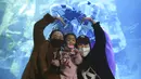 Pengunjung yang mengenakan masker untuk mencegah COVID-19 berpose dengan penyelam berkostum tradisional Korea saat perayaan Tahun Baru dalam akuarium di Seoul, Korea Selatan, Minggu (3/1/2021). (AP Photo/Ahn Young-joon)