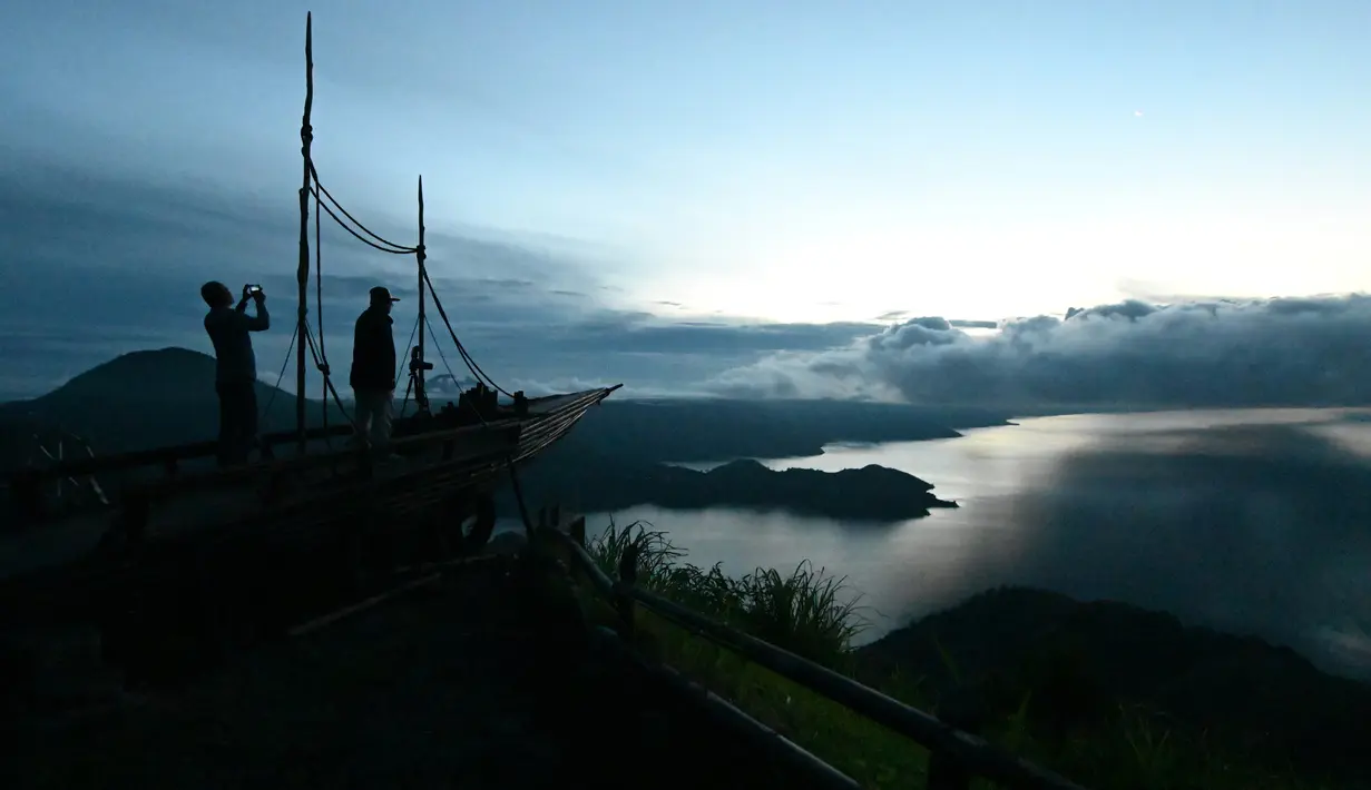 Pengunjung menikmati pemandangan Danau Toba dari Kabanjahe di Kabupaten Karo, Sumatra Utara, 3 April 2019. Danau berkawah seluas 1.145 kilometer persegi ini diperkirakan terbentuk dari letusan supervolcano Gunung Toba yang terjadi sekitar 74.000 tahun yang lalu. (GOH CHAI HIN / AFP)