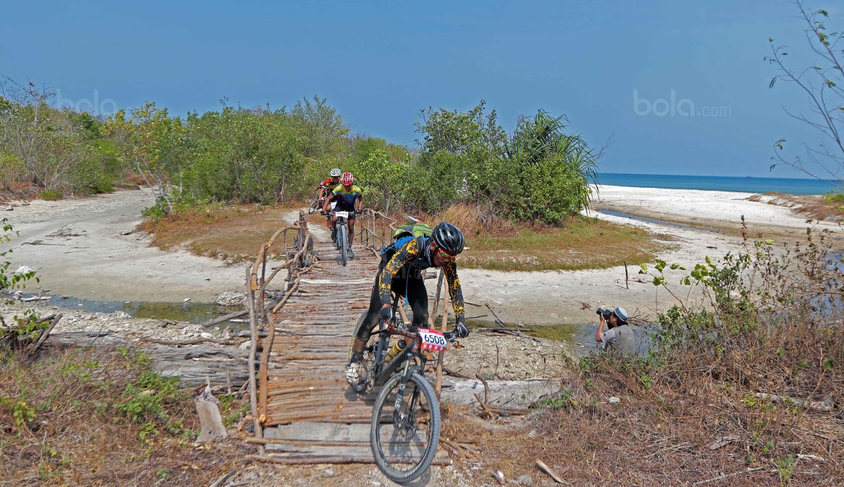 Para pebalap Mountain Bike Cross Country Marathon melintasi jembtan kayu pada Festival Pesona Tanjung Lesung 2017 di Tanjung Lesung, Banten (23/9/2017). MTB XCM tersebut menempuh jarak 48 km. (Bola.com/Nicklas Hanoatubun)
