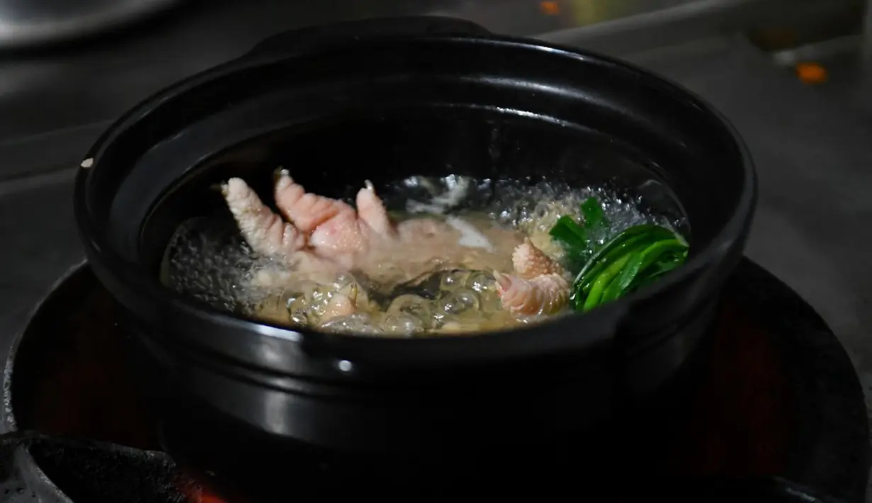 Kaki ayam Dong Tao sedang dimasak di sebuah restoran di Hanoi, Vietnam, 15 Januari 2023. Saat ini para peternak kini telah mengembangbiakkan ayam tersebut untuk dijual pada restoran mahal dan diperuntukan bagi orang kaya. (Nhac NGUYEN/AFP)