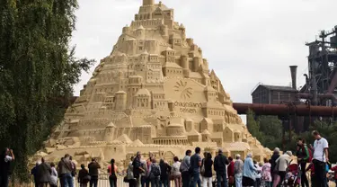 Seniman saat menyelesaikan istana pasir di Landschaftspark di Duisburg, Jerman , (1/9). Seniman dari Duisburg burusaha meraih Guinness Book of World Records dengan membuat istana pasir tertinggi yang pernah ada. (Marcel Kusch / dpa via AP)