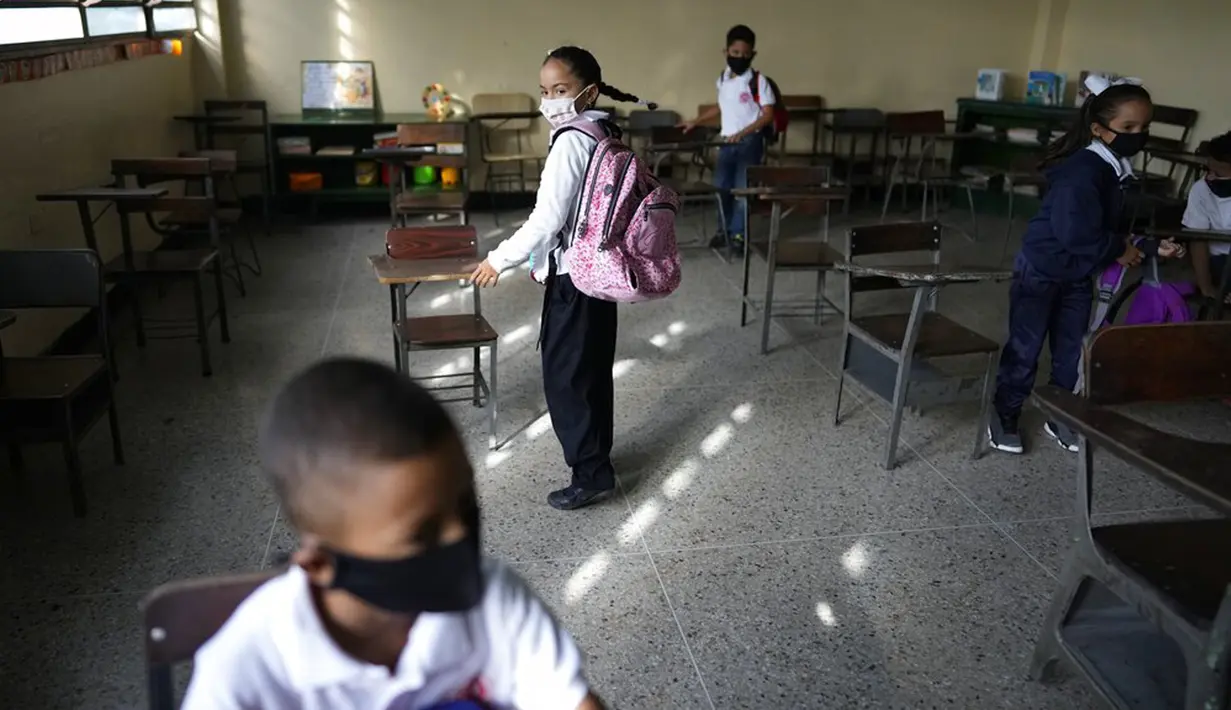 Para siswa menuju meja mereka pada hari pertama kembali ke kelas tatap muka sejak dimulainya pembatasan pandemi COVID-19 di sekolah umum di Caracas, Venezuela, 25 Oktober 2021. (AP Photo/Ariana Cubillos)