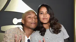 Pharrell Williams dan istrinya, Helen Lasichanh, berpose di karpet merah Grammy Awards 2016 di Los Angeles, Senin (15/2). Sang istri juga tampil modis dalam balutan mini dress putih bergaris. (Larry Busacca/Getty Images for NARAS/AFP)