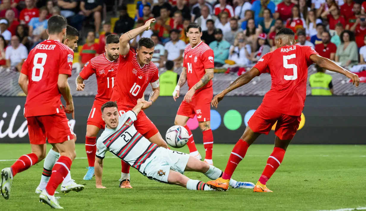 Pemain Portugal Diogo Jota (tengah) berebut bola dengan pemain Swiss Granit Xhaka (tengah belakang) pada pertandingan sepak bola Grup A2 UEFA Nations League di Stadion Stade de Geneve, Jenewa, Swiss, 12 Juni 2022. Portugal kalah tipis 0-1 dari Swiss. (Jean-Christophe Bott/Keystone via AP)