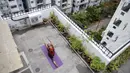 Instruktur yoga Pratibha Agarwal dari Anahata Yoga Zone melakukan gerakan yoga menjelang Hari Yoga Internasional di teras sebuah bangunan di Hyderabad, India pada 18 Juni 2020. Hari Yoga Internasional atau International Day of Yoga diperingati setiap tahun pada 21 Juni. (Photo by NOAH SEELAM / AFP)