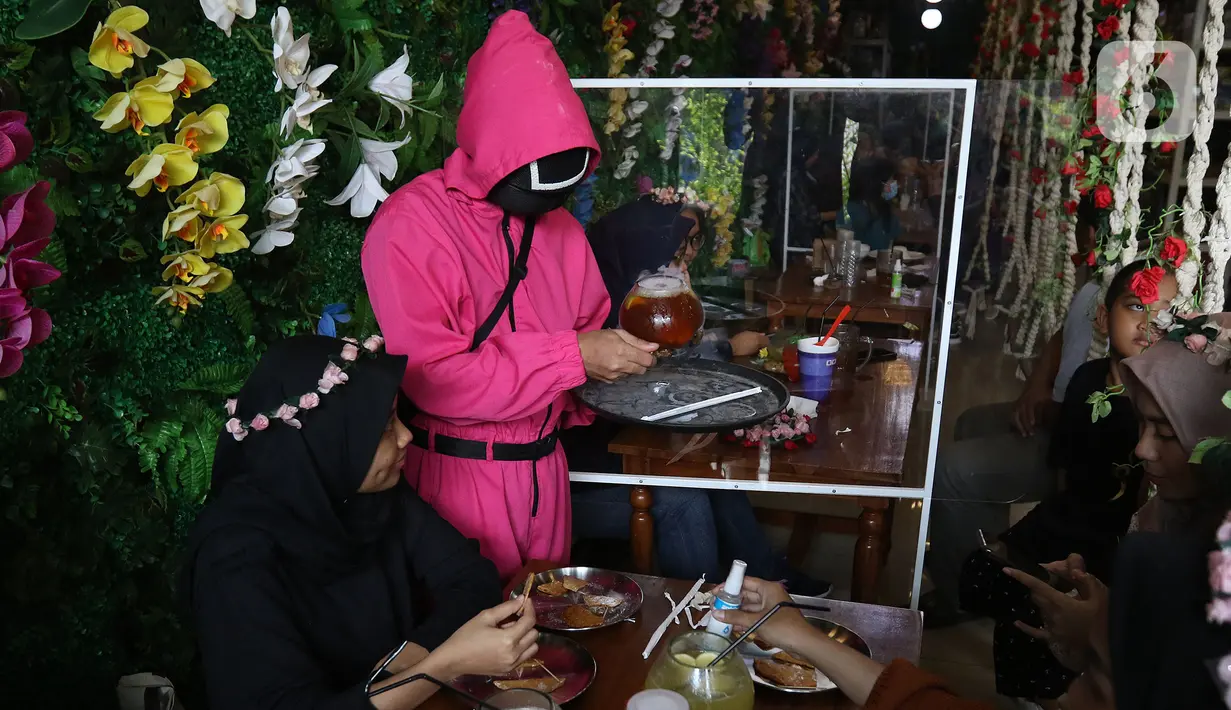 Pramusaji melayani pengunjung di Cafe Strawberry, Jakarta, Sabtu (16/10/2021). Cafe tersebut mengusung tema permainan yang ada dalam serial Netflix Squid Game untuk memberikan daya tarik bagi pengunjung yang ingin makan sekaligus mencoba permainan itu. (Liputan6.com/Herman Zakharia)