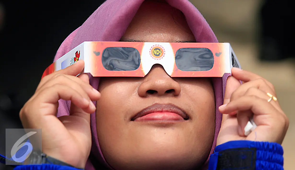Seorang mahasiswi mencoba kacamata yang akan di gunakan untuk mengamati gerhana matahari di taman Pintar Yogyakarta, (2/3). Kawasan Tugu menjadi salah satu tempat pengamatan gerhana matahari pada 9 Maret 2016. (Liputan6.com/Boy Harjanto)