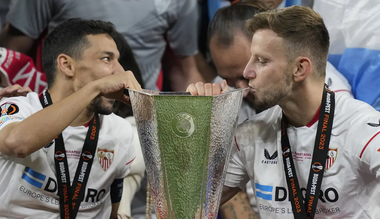 Pemain Sevilla, Ivan Rakitic (kanan) dan Jesus Navas mencium trofi Liga Europa setelah berhasil mengalahkan AS Roma di partai final Liga Europa 2022/2023 yang berlangsung di Puskas Arena, Budapest, Kamis (1/6/2023) dini hari WIB. Ini merupakan gelar kedua yang dirasakan oleh Rakitic dan juga Jesus Navas bersama Sevilla. (AP Photo/Darko Bandic)