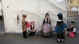 Anak-anak Yahudi ultra-Ortodoks mengenakan kostum lengkap dengan atributnya bersiap mengikuti perayaan purim di Yerusalem (8/3). Perayaan Purim ini dimulai pada saat matahari terbenam. (AFP/Menahem Kahana)