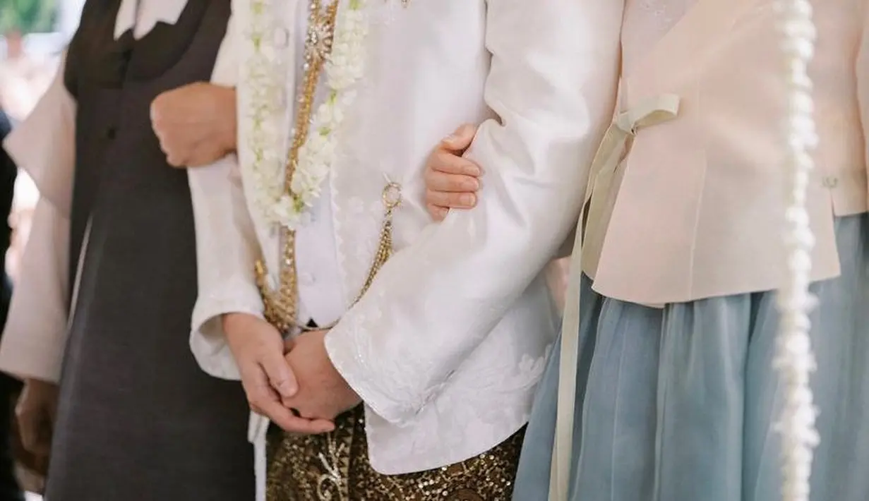 Dalam beberapa slide foto, Maudy dan suami terlihat mengenakan busana pengantin yang seragam, berwarna putih dengan nuansa Sunda yang kental. Di foto pertama, terlihat sang suami mengenakan baju pengantin yang terdiri dari jas dengan bawahan dari kain bermotif batik. Foto: Instagram.