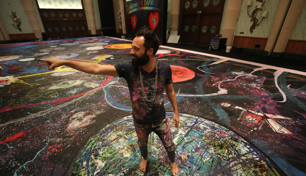 Seniman Inggris Sacha Jafri memaparkan lukisannya yang berjudul "The Journey of Humanity" di Dubai, UEA pada 1 Oktober 2020. Donasi dari karya seni ini akan digunakan untuk inisiatif kesehatan dan pendidikan bagi anak-anak yang hidup dalam kemiskinan di seluruh dunia. (AP Photo/Kamran Jebreili)