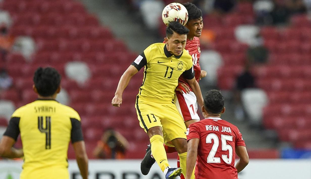 Bek Timnas Indonesia, Asnawi Mangkualam, berduel dengan pemain Malaysia, Arif Rahman, pada laga penyisihan Grup B Piala AFF 2020.(AFP/Roslan Rahman)