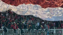 Suporter Timnas Indonesia mengibarkan bendera raksasa saat melawan Thailand pada laga Final Piala AFF 2016 di Stadion Pakansari, Bogor, (14/12/2016). (Bola.com/Nicklas Hanoatubun)