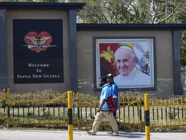 Warga setempat berjalan melewati foto Paus Fransiskus jelang kunjungannya ke Port Moresby, Papua Nugini, Rabu (4/9/2024). (AP Photo/Mark Baker)