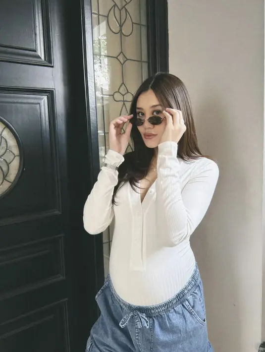 Kali ini ia kenakan denim dan kaos lengan panjang putih. Sebuah paduan kontras untuk look yang vegitu kasual. [Foto: Instagram/ Aaliyah Massaid]