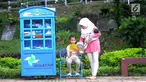 Seorang ibu menemani anaknya membaca buku yang tersedia di layanan Kotak Literasi Cerdas (Kolecer) di Taman Sempur, Bogor, Jawa Barat, Kamis (20/12). Kolecer adalah perpustakaan jalanan gratis. (Merdeka.com/Arie Basuki)