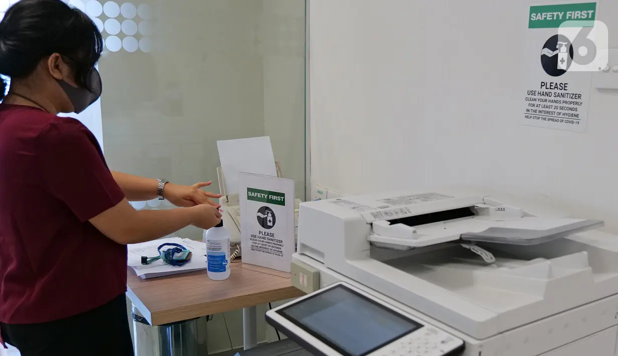 Karyawan menggunakan cairan pembersih tangan setelah menggunakan mesin fotokopi di ruang kantor Suntory Garuda, Jakarta, Senin (8/8/2020). Suntory Garuda menerapkan protokol Kesehatan, salah satunya kapasitas karyawan hanya dibolehkan sebanyak 50 persen. (Liputan6.com/Herman Zakharia)