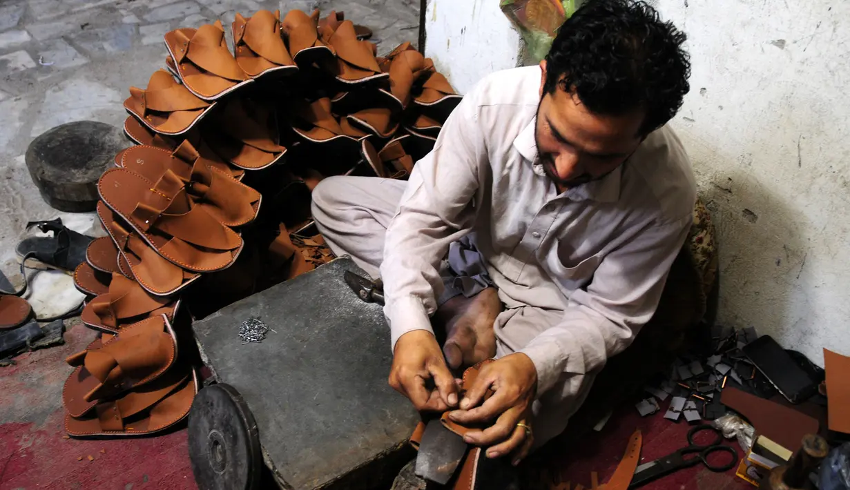 Seorang pembuat sepatu asal Pakistan membuat sepatu tradisional yang dikenal sebagai "chapli" di kalangan penduduk lokal untuk menyambut Hari Raya Idul Fitri di Peshawar, Pakistan barat laut, pada 19 Mei 2020. (Xinhua/Saeed Ahmad)