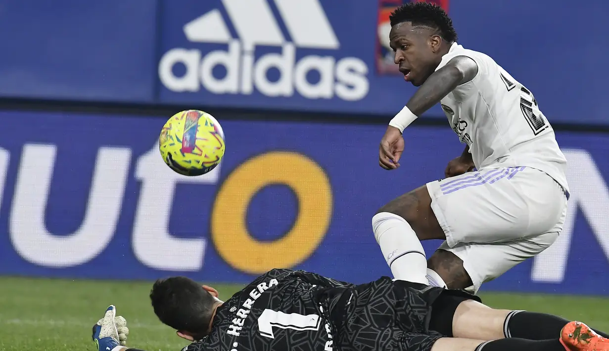 <p>Kiper Osasuna, Sergio Herrera menghalau bola tendangan penyerang Real Madrid, Vinicius Junior selama pertandingan lanjutan La Liga Spanyol di stadion El Sadar di Pamplona, Spanyol, Minggu (19/2/2023). Tambahan tiga angka membuat Madrid kini mengoleksi 51 poin. (AP Photo/Alvaro Barrientos)</p>