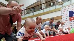 Sejumlah orang tua memberikan arahan kepada anaknya saat mengikuti lomba 'Balap Bayi' di Vilnius, Lithuania (1/6). Lomba ini diadakan dalam rangka memperingati Hari Anak Internasional. (REUTERS/Ints Kalnins)