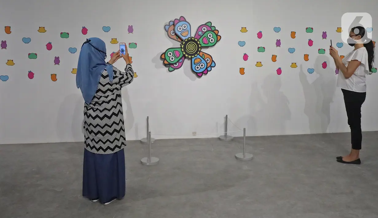 Pengunjung mengambil gambar karya yang dipajang dalam pameran Pulih di Pasar Seni, Ancol, Jakarta, Sabtu (14/11/20). Pameran PULIH merupakan bagian dari kampanye #PemulihanBersama yang diaktifkan Pasar Seni Ancol bersama dengan berbagai seniman dan tokoh seni budaya. (Liputan6.com/Herman Zakharia)