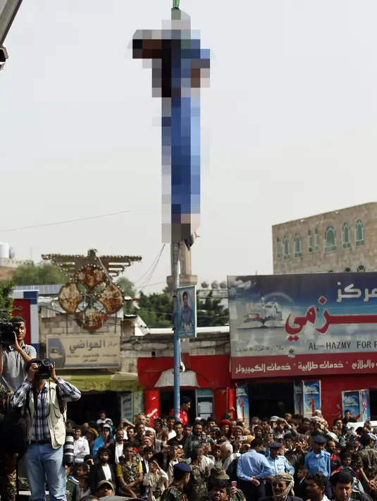 Jasad pria bernama Hussein al-Saket 22 tahun terlihat tergantung setelah dieksekusi oleh pasukan keamanan akibat memperkosa dan membunuh gadis berusia empat tahun di alun-alun Tahrir, Ibu Kota Sanaa, Yaman (14/8). (AFP Photo/Mohammed Huwais)