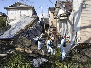 Petugas pemadam kebakaran berjalan melewati rumah-rumah yang roboh akibat gempa bumi di Suzu, prefektur Ishikawa, Jepang, Kamis (4/1/2024). (Kyodo News via AP)