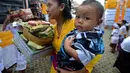 Seorang warga tampak membawa anaknya mendatangi pura untuk merayakan hari raya Galungan di Jimbaran, Bali, Rabu (21/5/14). (AFP PHOTO/Sonny Tumbelaka)